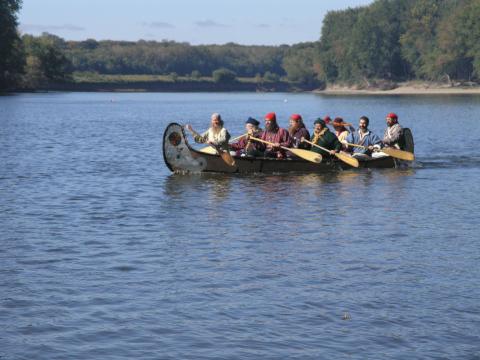 Trappers in a canoe on a river dressed in 1800s clothing 